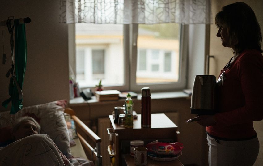 Fotobanka MILA Silueta pečovatelky, jak stojí u lůžka klientky