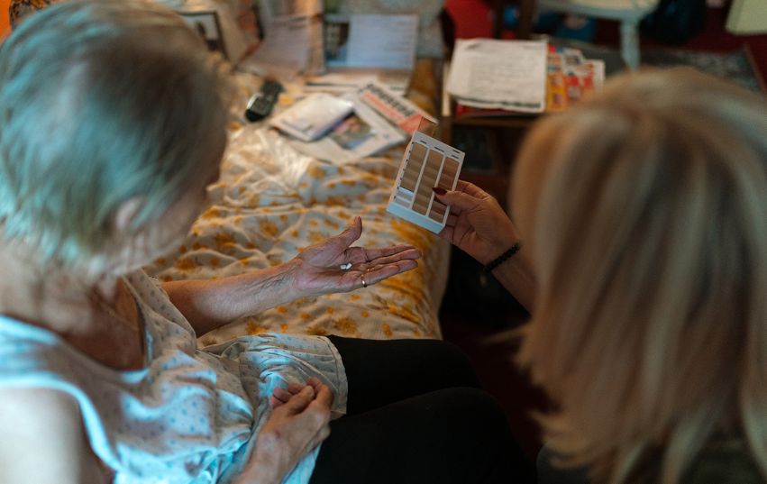Pečovatelka podává seniorce její léky