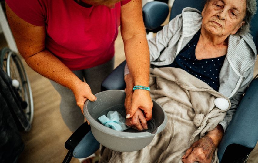 Pečovatelka um&yacute;v&aacute; ruce seniorce