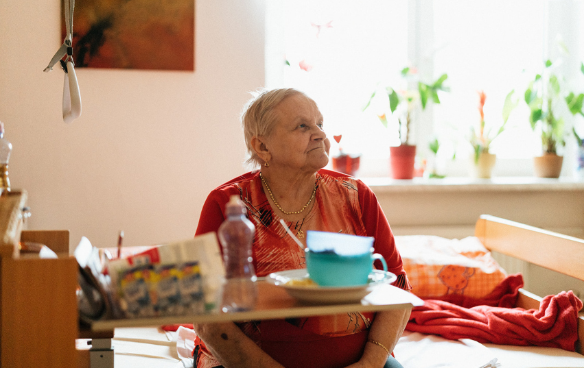 Seniorka sedící na posteli